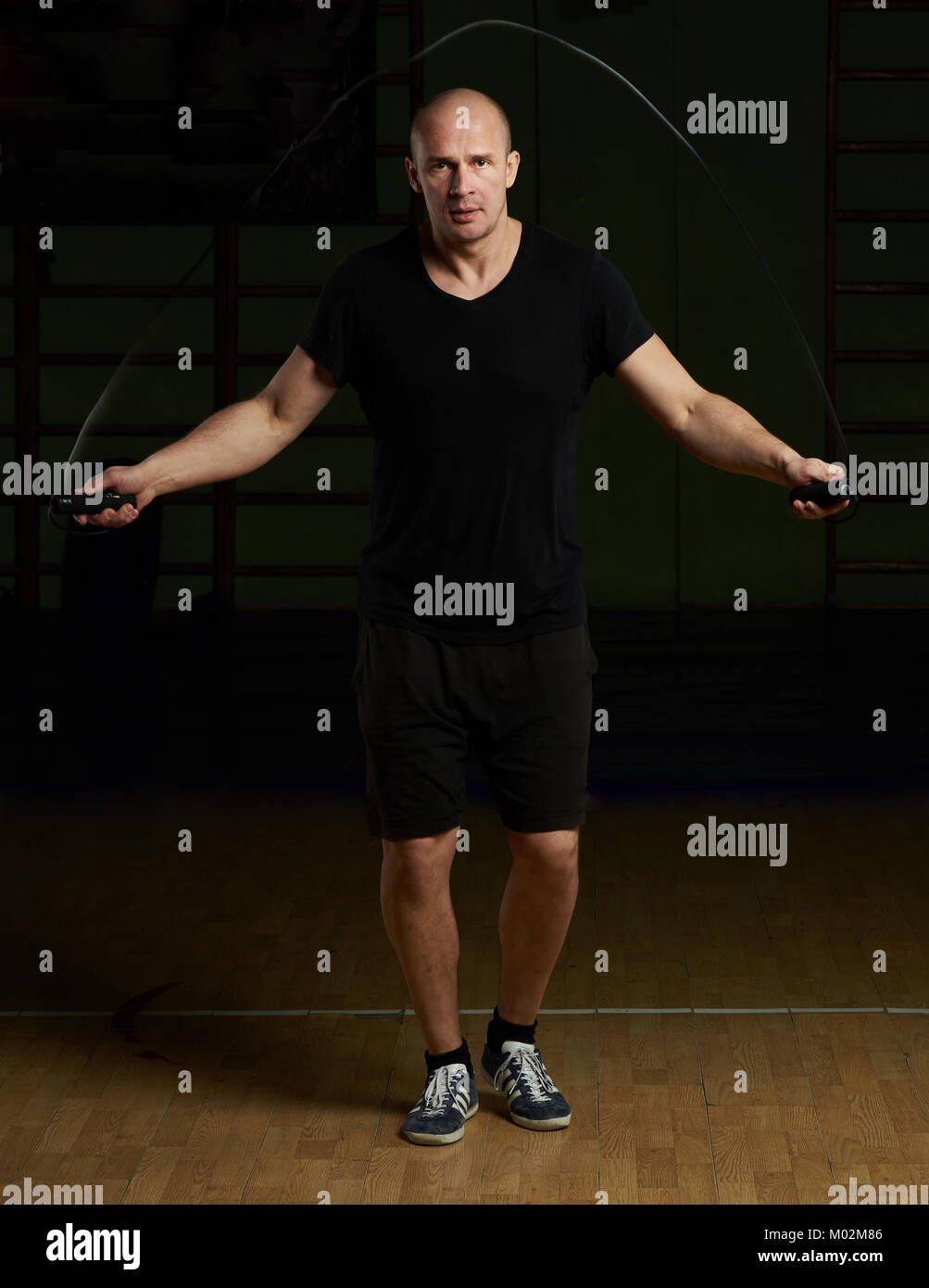 Mann springen mit Seil auf gym Hintergrund. Rope Skipping Übung Stockfoto