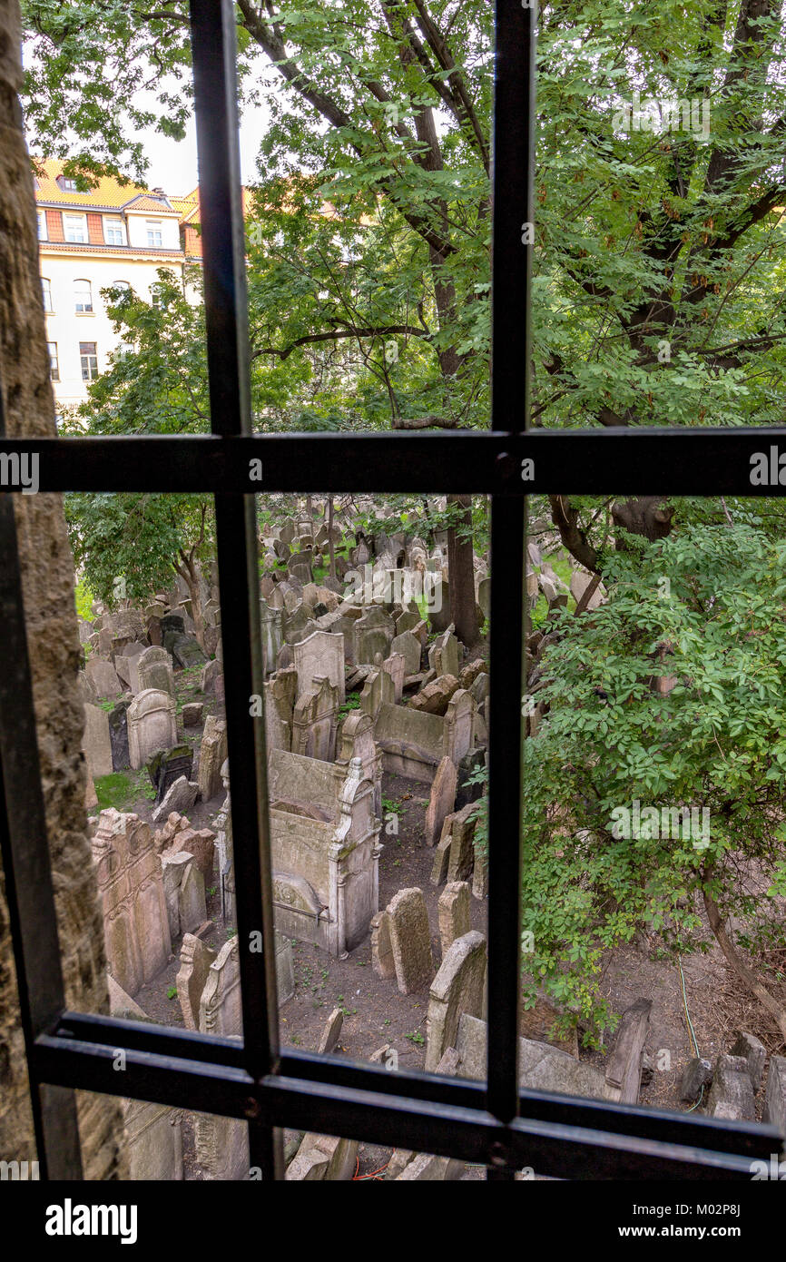 Auf der Suche durch einen vergitterten Fenster bei Tausenden von schiefen Grabsteine auf dem Alten Jüdischen Friedhof, Prag, Tschechische Republik Stockfoto