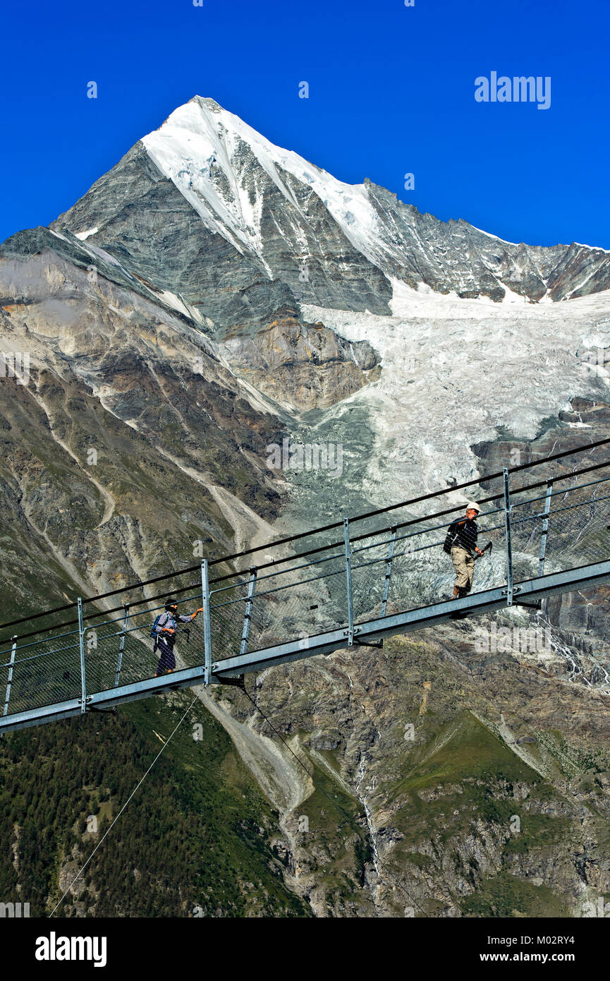 Wanderer auf dem Charles Kuonen Suspension Bridge, den weltweit gro§ten Erdolforderlandern zahlt längste Hängebrücke, mit dem Weisshorn Peak im Hintergrund, Randa, Kanton Va Stockfoto
