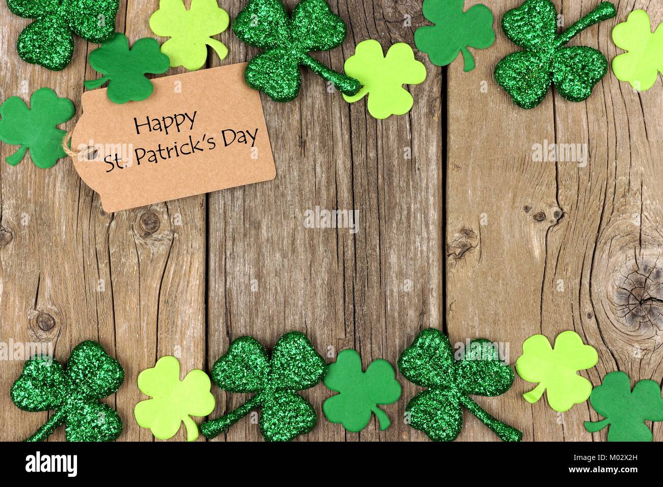 Happy St Patricks Day tag mit doppelter Grenze der glänzenden Shamrocks über eine rustikale Holz Hintergrund Stockfoto