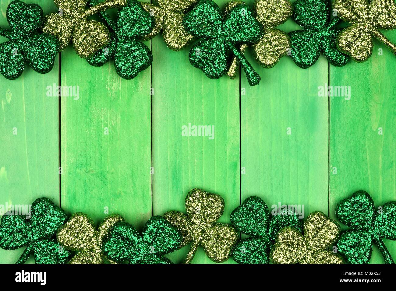 St Patricks Day double Grenze der glänzenden glitter Shamrocks über ein grünes Holz Hintergrund Stockfoto