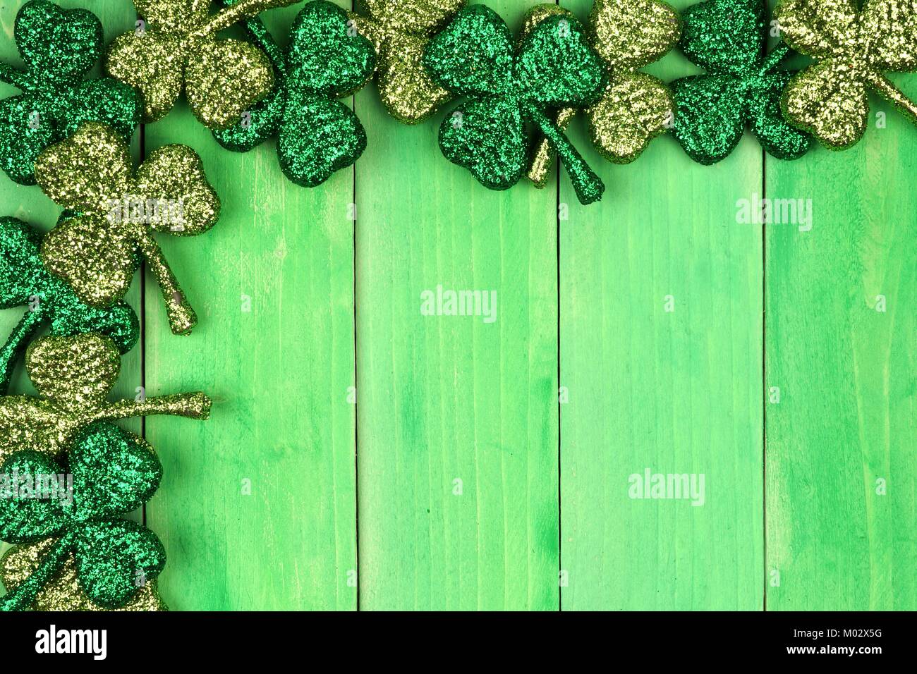 St Patricks Day Ecke Grenze der glänzenden glitter Shamrocks über ein grünes Holz Hintergrund Stockfoto