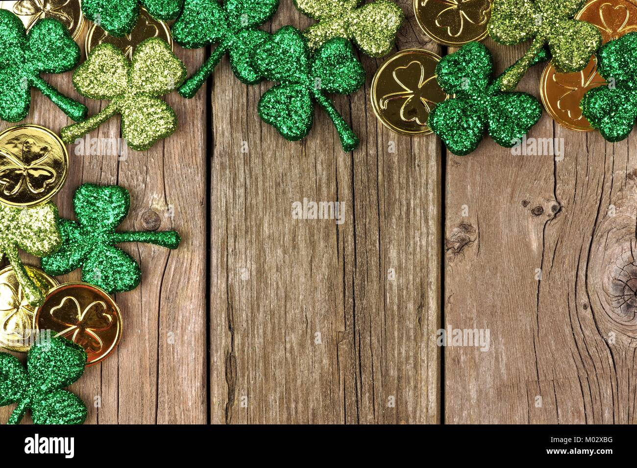 St Patricks Day Ecke Grenze des Shamrocks und Goldmünzen über eine rustikale Holz Hintergrund Stockfoto