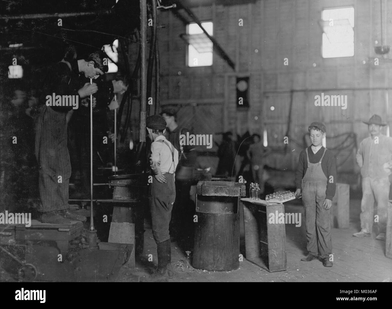 Männer mit Fuß-Werkzeug und Boys. Ein West Virginia Glashütten Stockfoto
