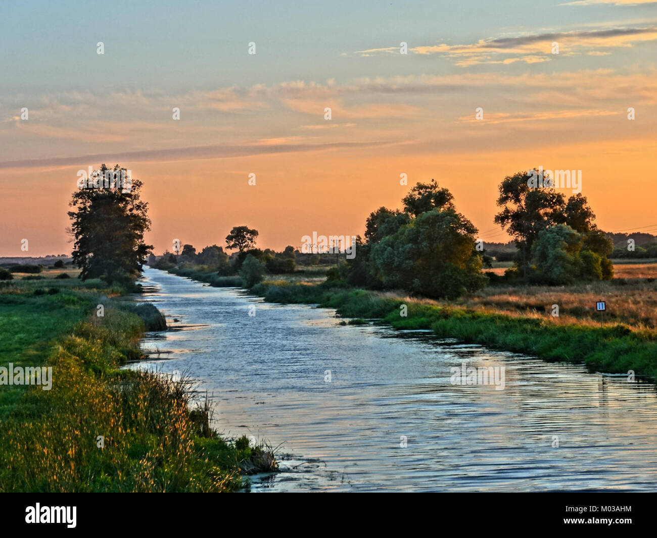Der Bydgoszcz-Kanal bei Sonnenuntergang bietet eine wunderschöne natürliche Szene, in der die Sonne warme Farbtöne über das Wasser wirft und eine friedliche und malerische Landschaft schafft. Stockfoto