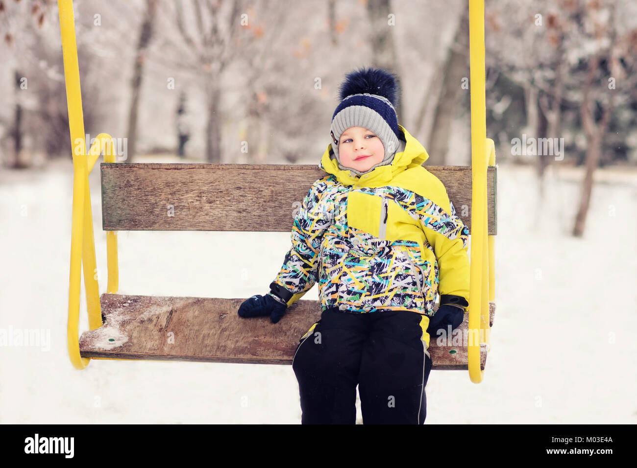 Das Kind. Junge im Winter Kleidung reiten auf einer Schaukel, Emotion, Lachen, Winter, Schnee Stockfoto
