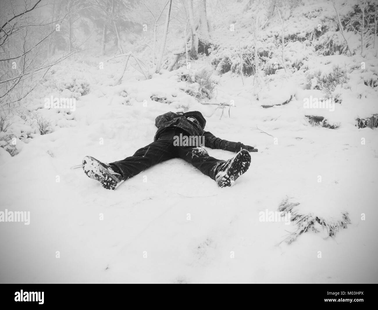 Lustig junge Verlegung in die schneeverwehung. Kind Spiel im frischen Pulverschnee auf steinigen Hügel. Schneesturm und nebligen Wetter. Stockfoto