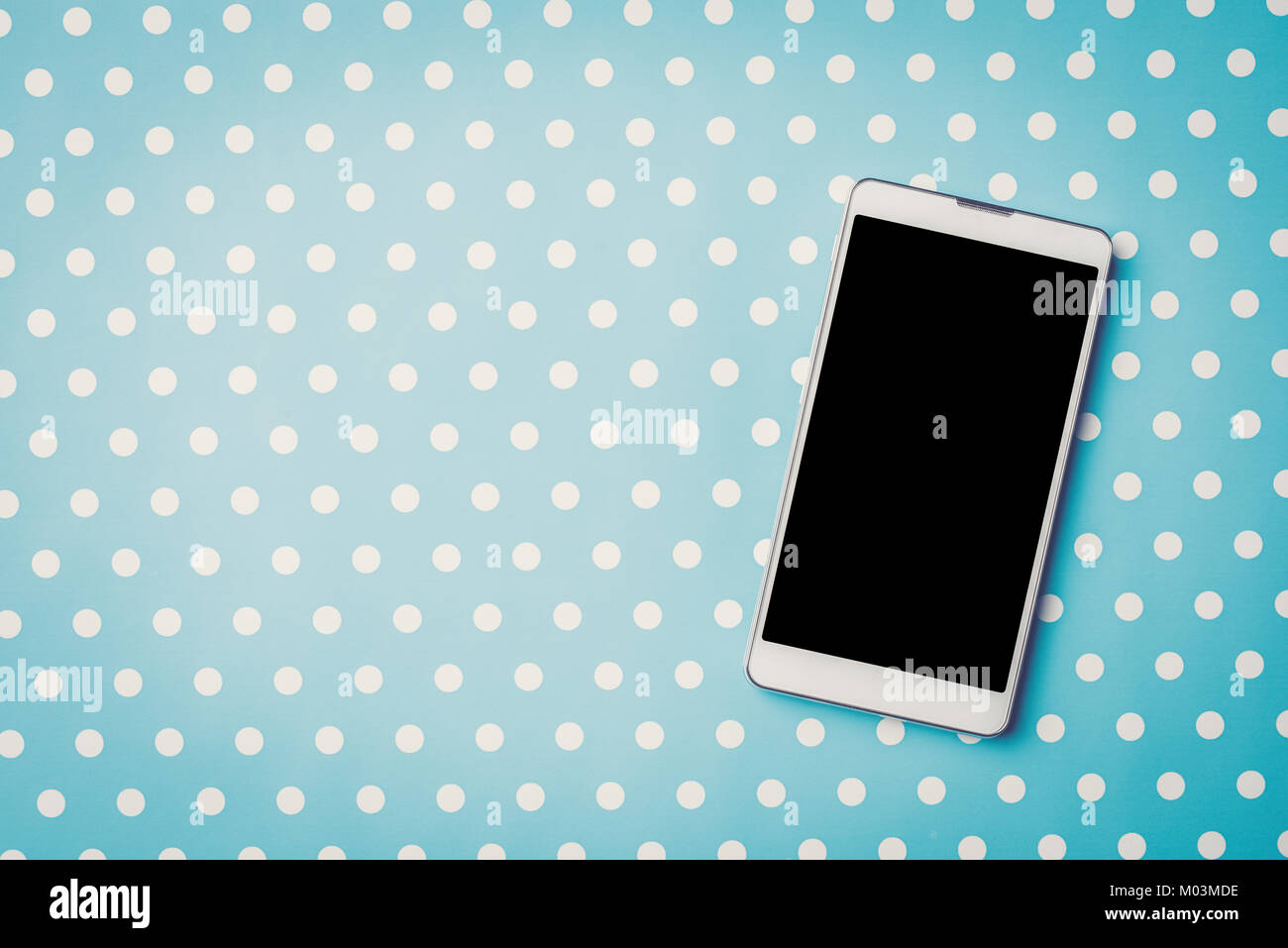 White Mobiltelefon über blau gepunkteten Hintergrund Stockfoto