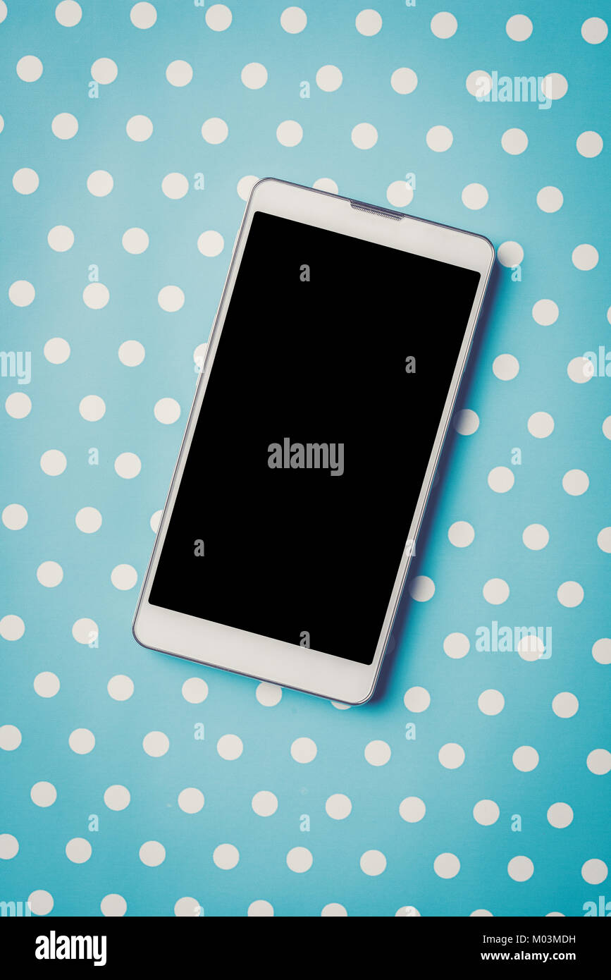 White Mobiltelefon über blau gepunkteten Hintergrund Stockfoto