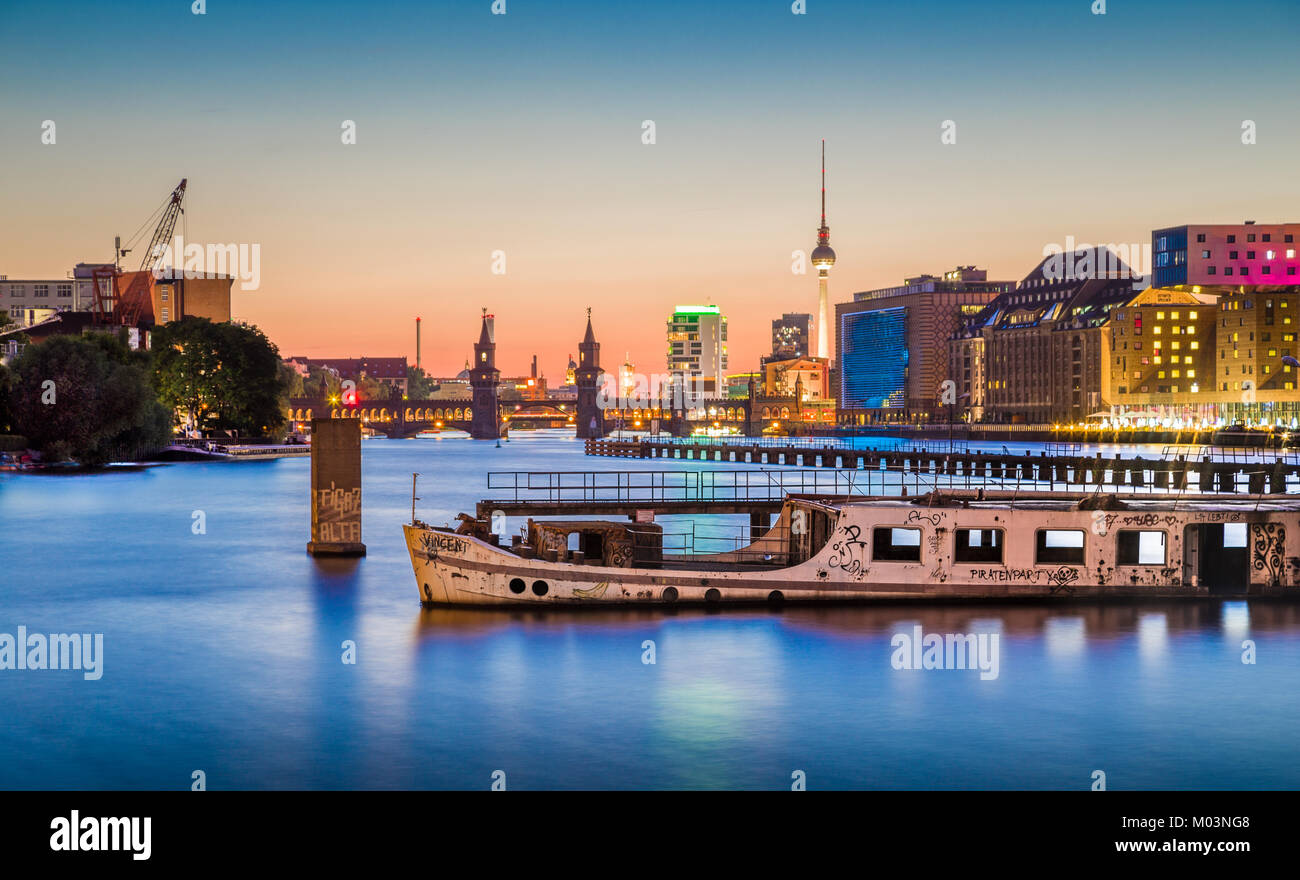 Panoramablick auf Berlin Skyline mit berühmten Fernsehturm und Oberbaumbrücke mit alten Schiffswrack liegen in der Spree bei Dämmerung, Berlin Friedrichshain-Kreu Stockfoto
