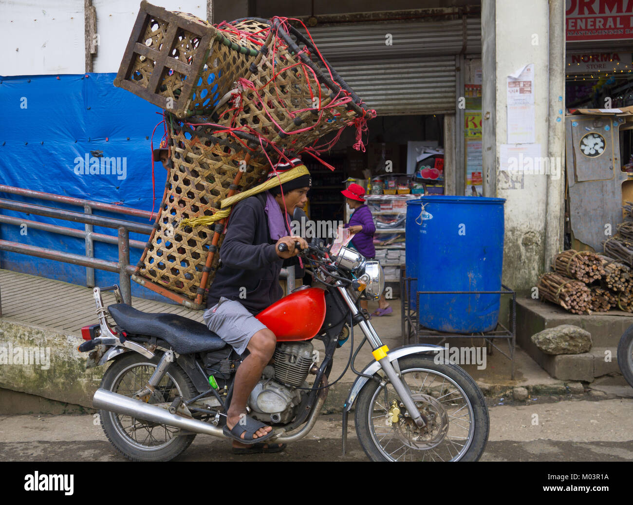 Motorradfahrer Balancing eine große Last von Körben, Mantalongon Markt, Dalaguete, Cebu Stockfoto