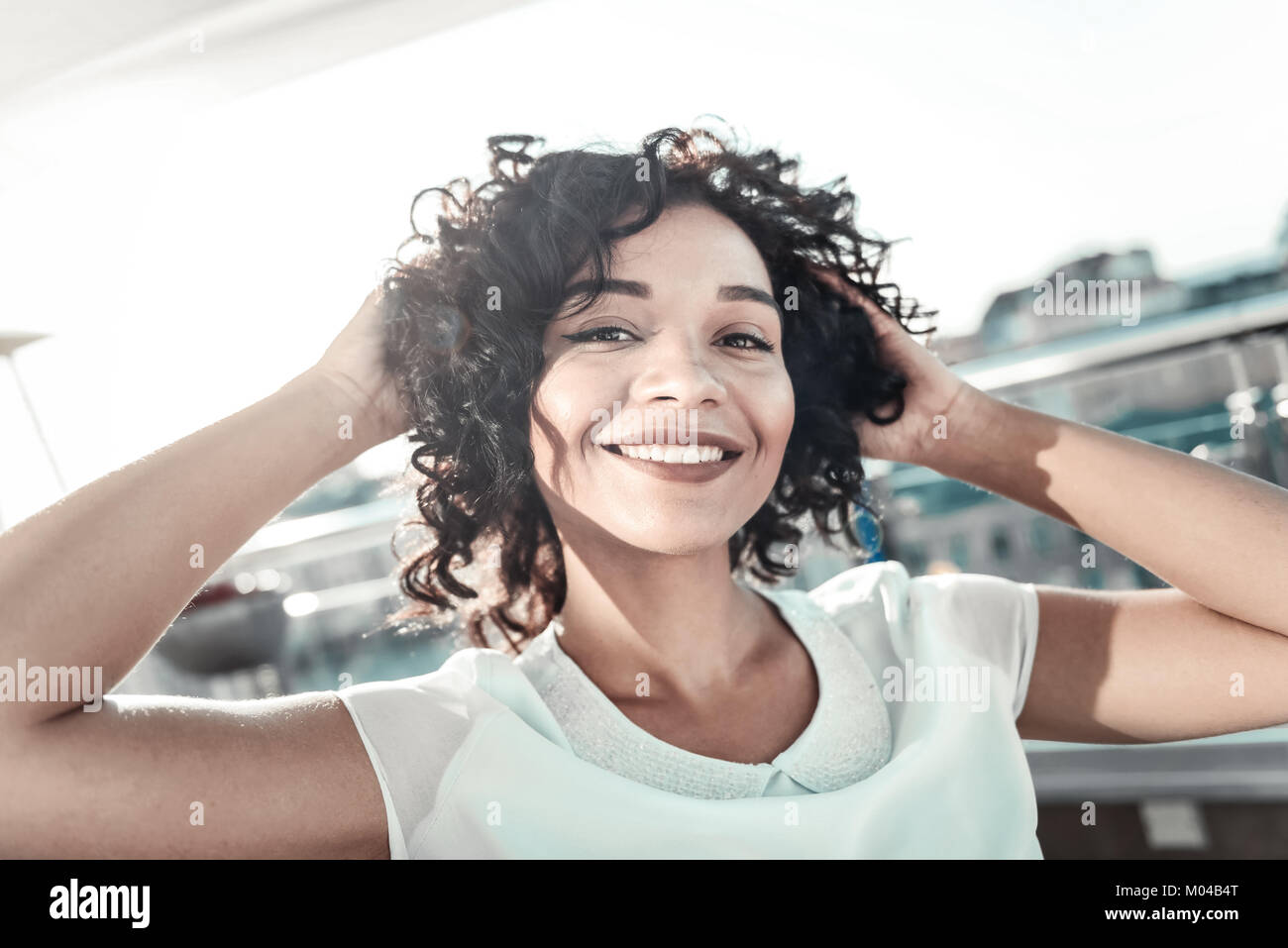 Fröhliches Mädchen, die Hände hinter dem Kopf und lächelt zufrieden. Stockfoto