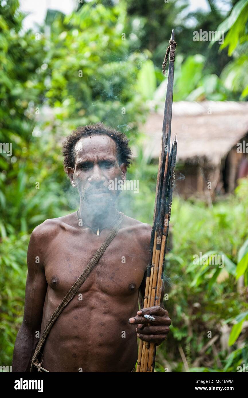 Das autonomiegesetz von einem Korowai Stamm. Korowai kombai (Kolufo) mit Bogen und Pfeile, die auf den natürlichen Wald Hintergrund Stockfoto