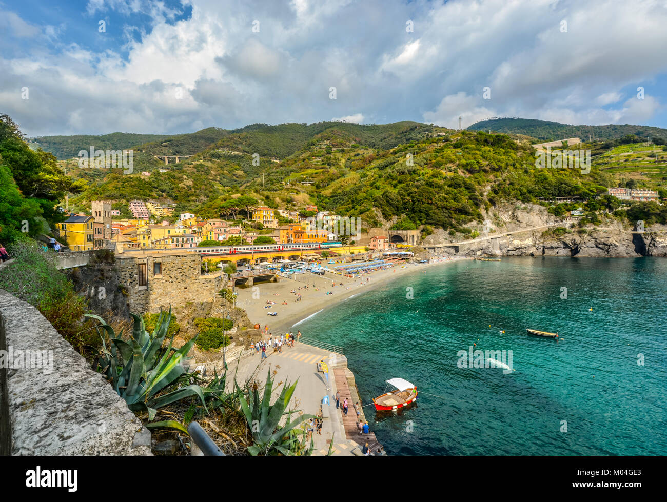 Der Sandstrand Spiaggia di Fegina, der Bahnhof mit Zügen läuft, die Berge, das Meer und bunten Dorf Monterosso, Cinque Terre Italien Stockfoto