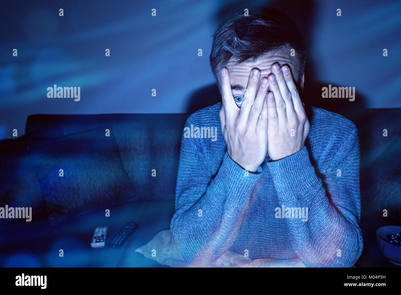 Mann, die seine Augen während der TV-Programmwiedergabe Stockfoto