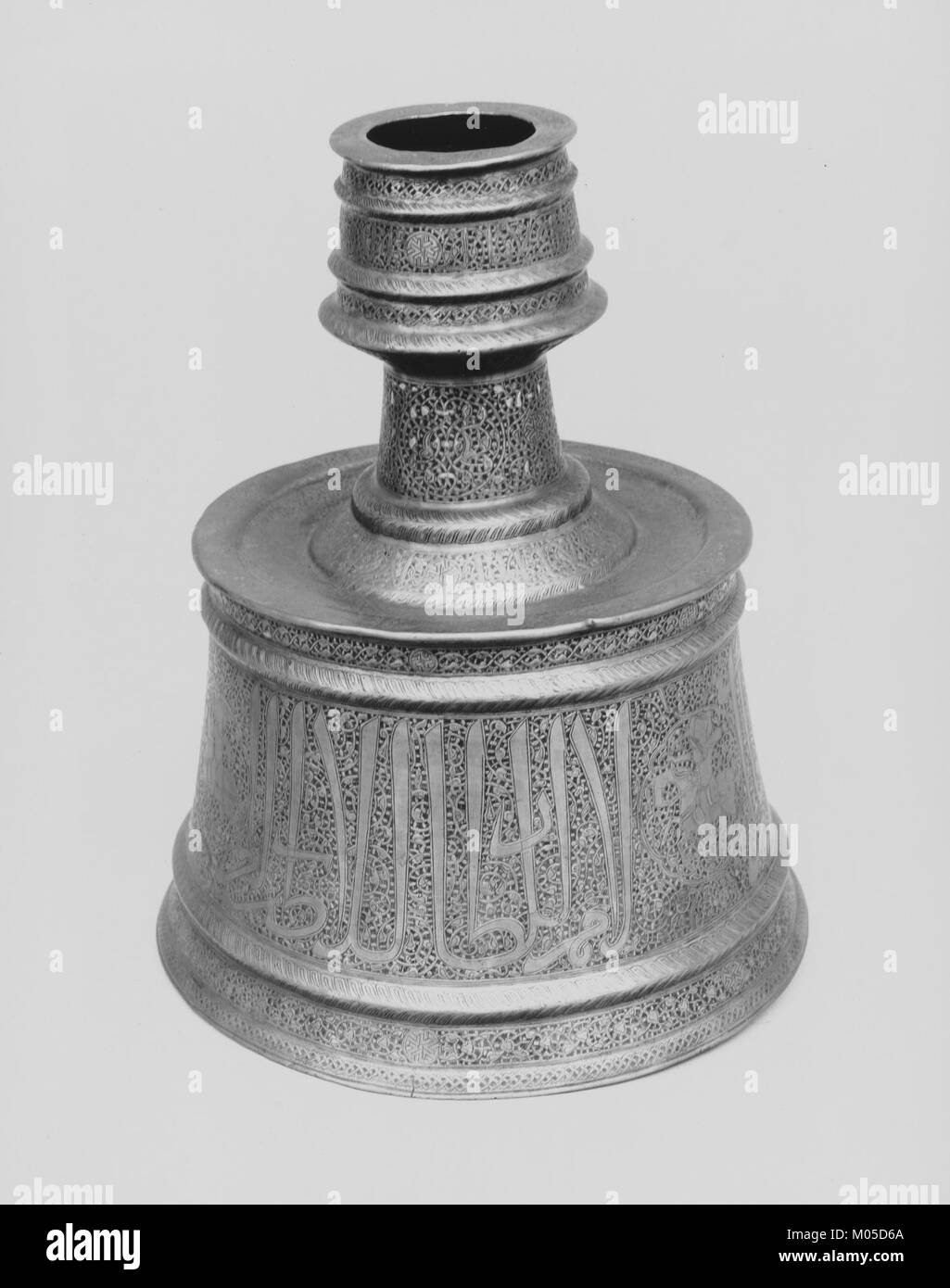 Ein Kerzenleuchter aus der MET-Sammlung mit komplizierten arabischen Inschriften, die Segen auf den Sultan vermitteln, sowie Reiterfiguren, die islamische Kunst widerspiegeln. Stockfoto