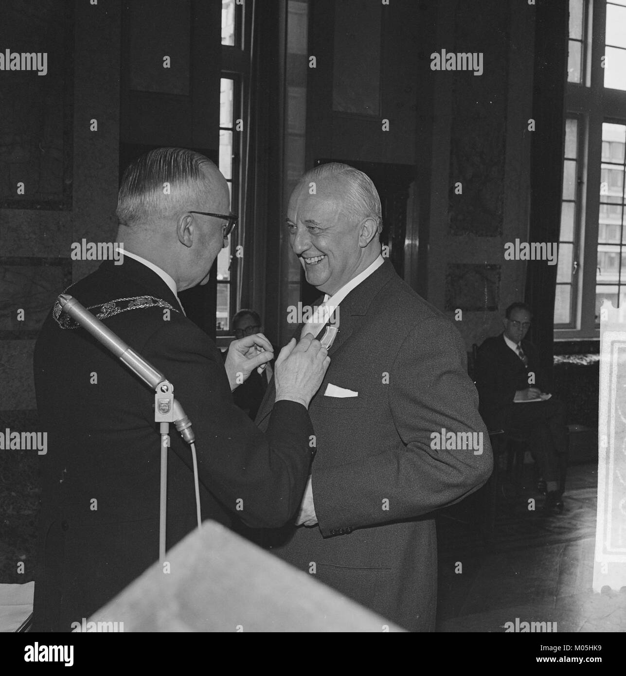 Burgemeester Van Walsum präsentiert in diesem historischen Bild eine Medaille (lintje uit), die einen Moment der bürgerlichen Anerkennung in den Niederlanden feststellt. Das Bild erinnert wahrscheinlich an eine Auszeichnung oder Ehre, die einer Person verliehen wurde. Stockfoto