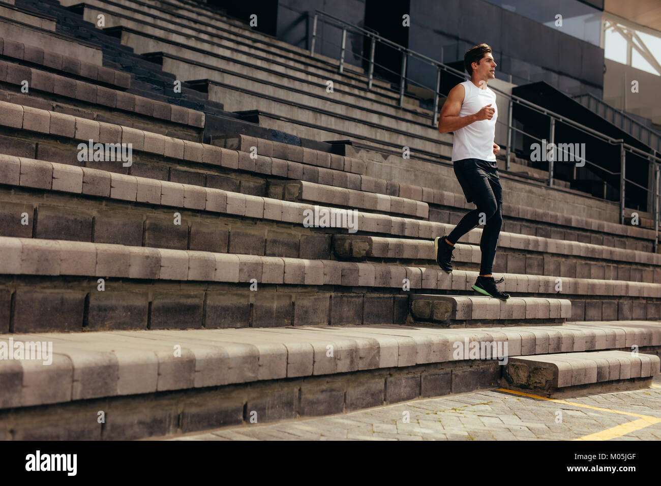 Läufer liefen die Schritte des Stadions steht als Teil seiner körperlichen Training. Junge Mann laufen unten am Stadion. Stockfoto