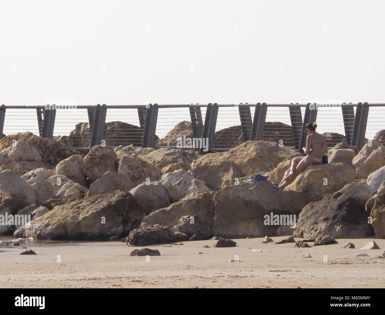 Frau sitzt am Strand Felsen auf eine perfekte klaren Tag Stockfoto