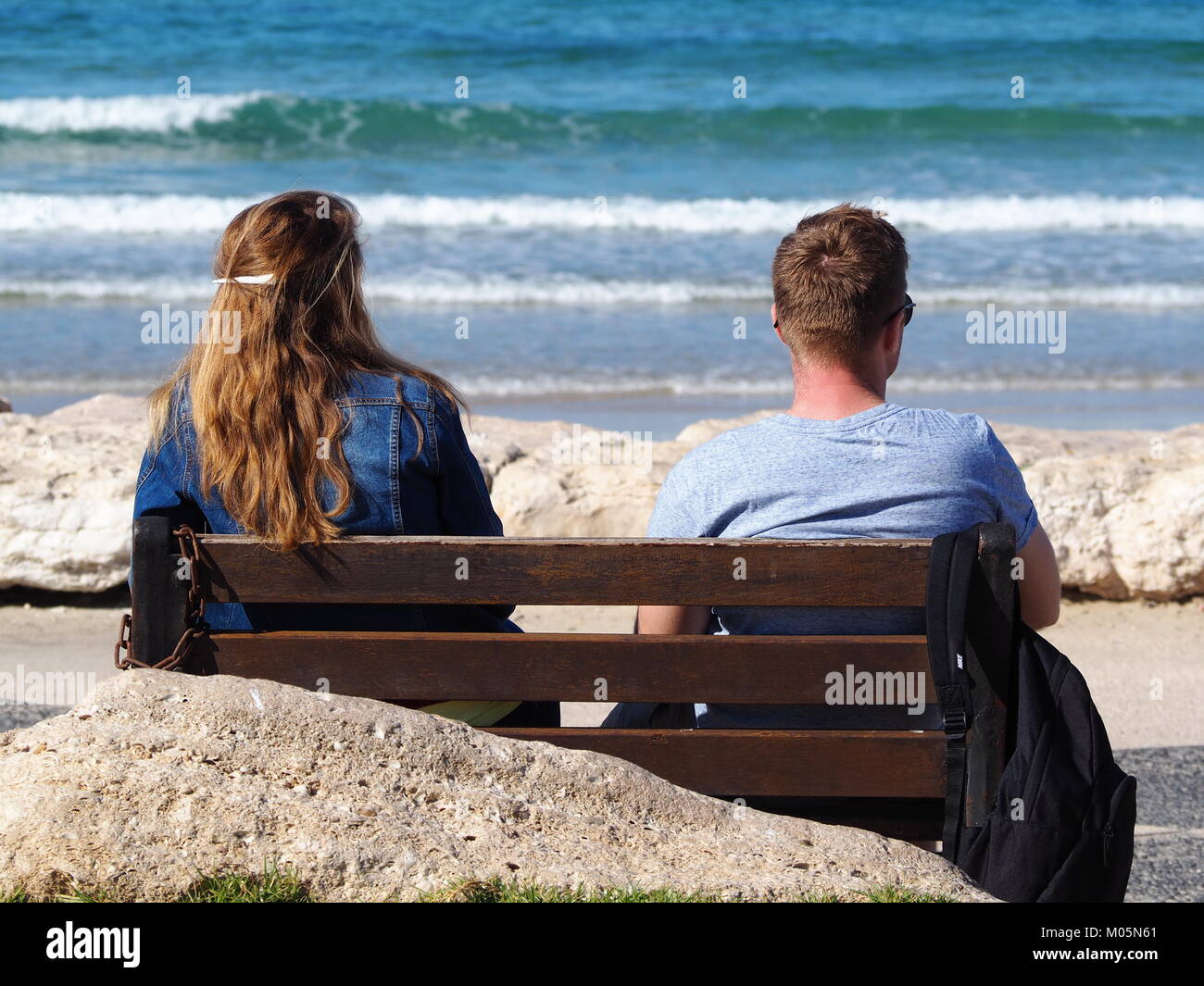 Zwei Freunde sitzen auf einer Bank an der Strandpromenade auf eine perfekte Sicht auf das Meer Stockfoto
