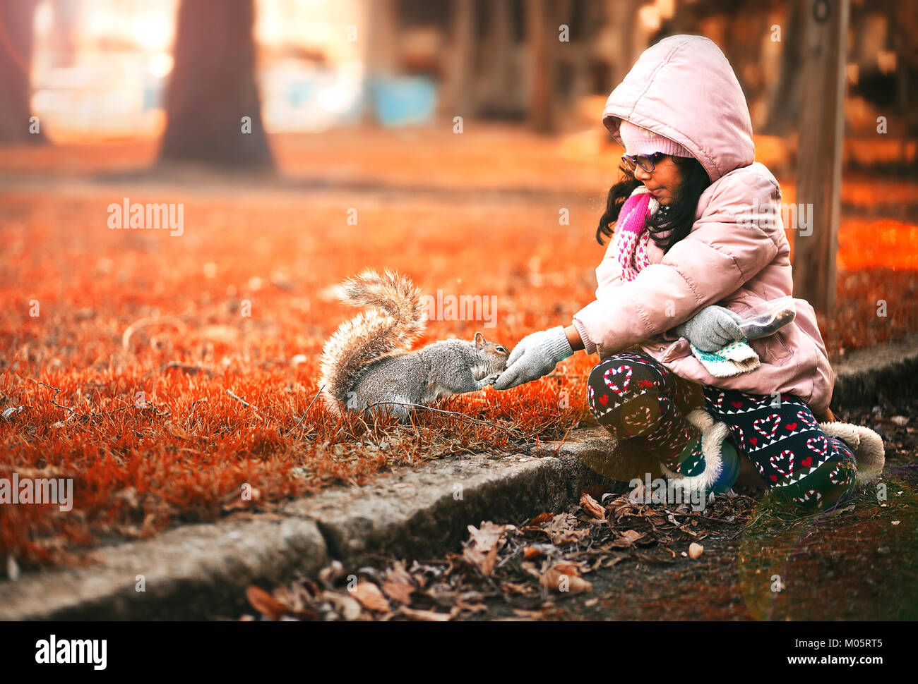 Kleines Mädchen im Winter Mantel Fütterung Muttern in einem Park im Herbst Eichhörnchen Stockfoto