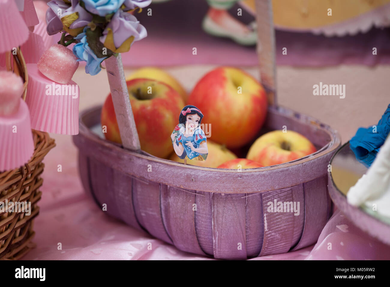 Korb mit Äpfeln auf einer Party mit einem disney princess Thema mit einem Bild von Snow white Charakter Stockfoto