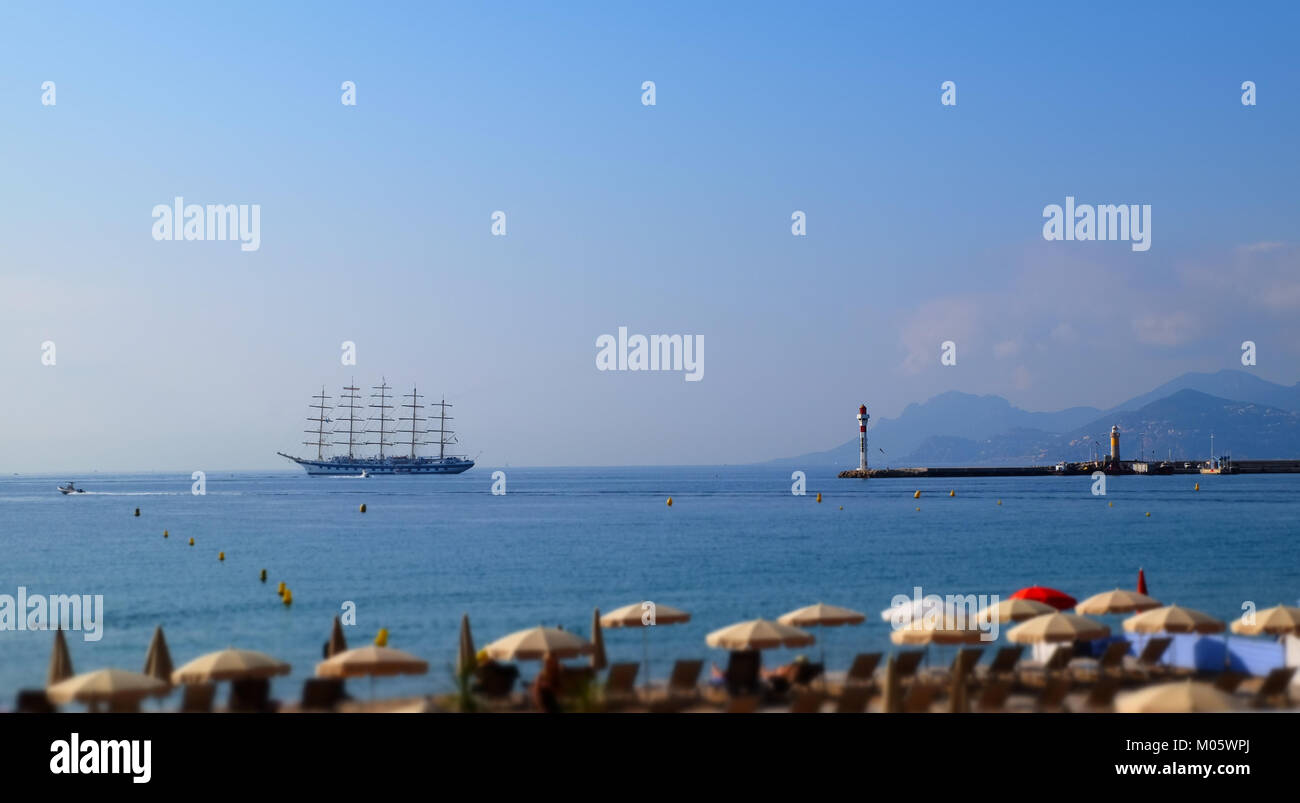 Meer mit Segelboot und Leuchtturm am Horizont öffnen Stockfoto