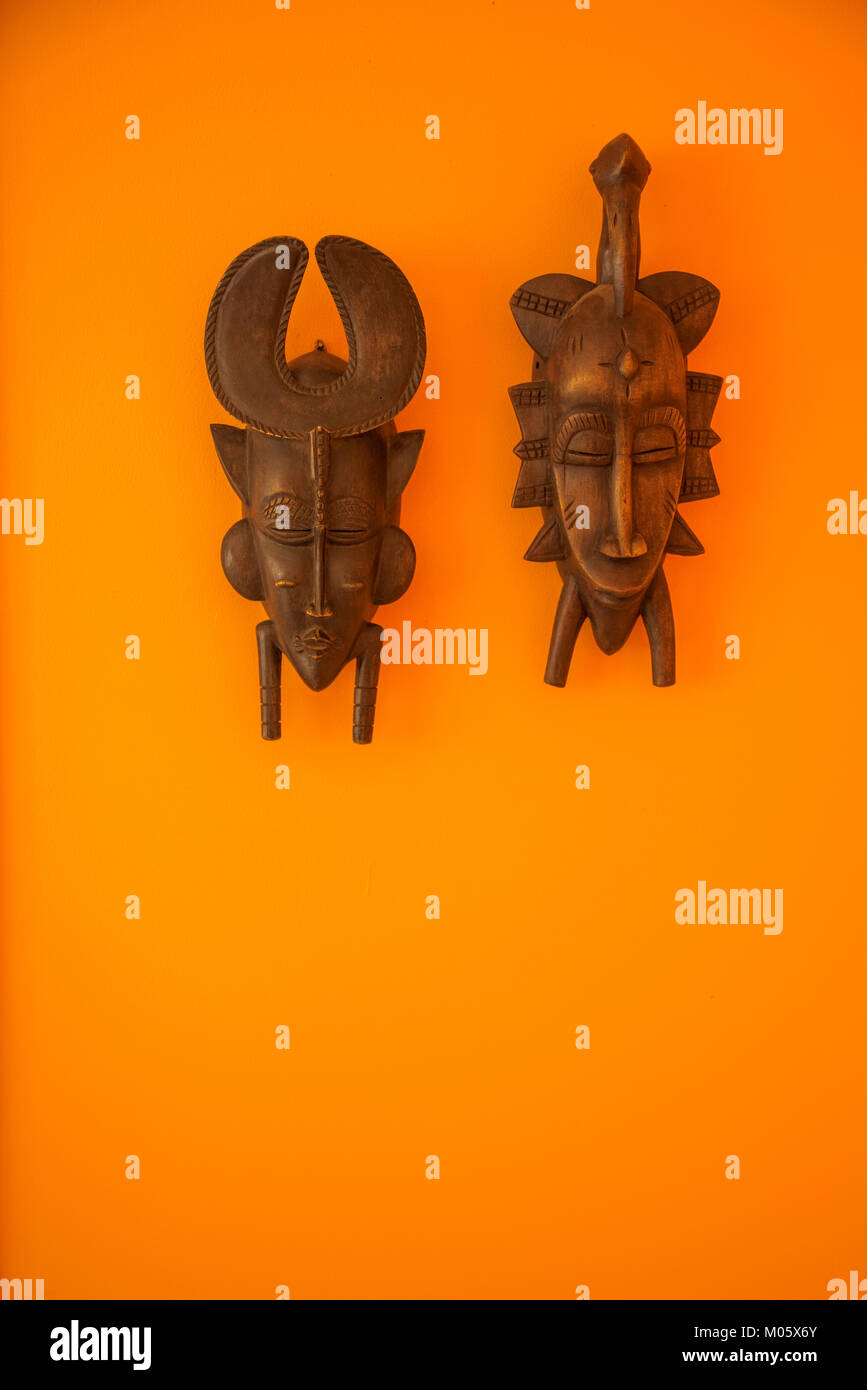 Afrikanische Masken auf Orange Wand Stockfoto