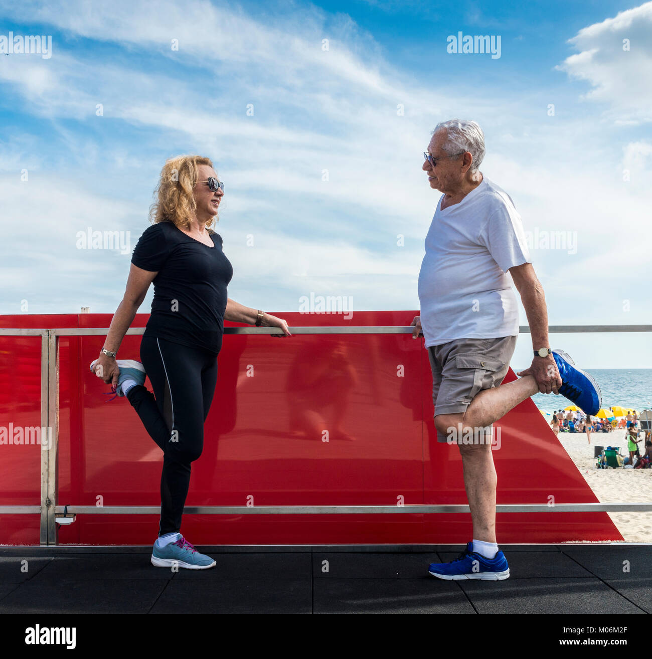 Model Released - Reife heterosexuelles Paar Dehnung Quadrizeps am Strand - Seite Fitnessraum Stockfoto