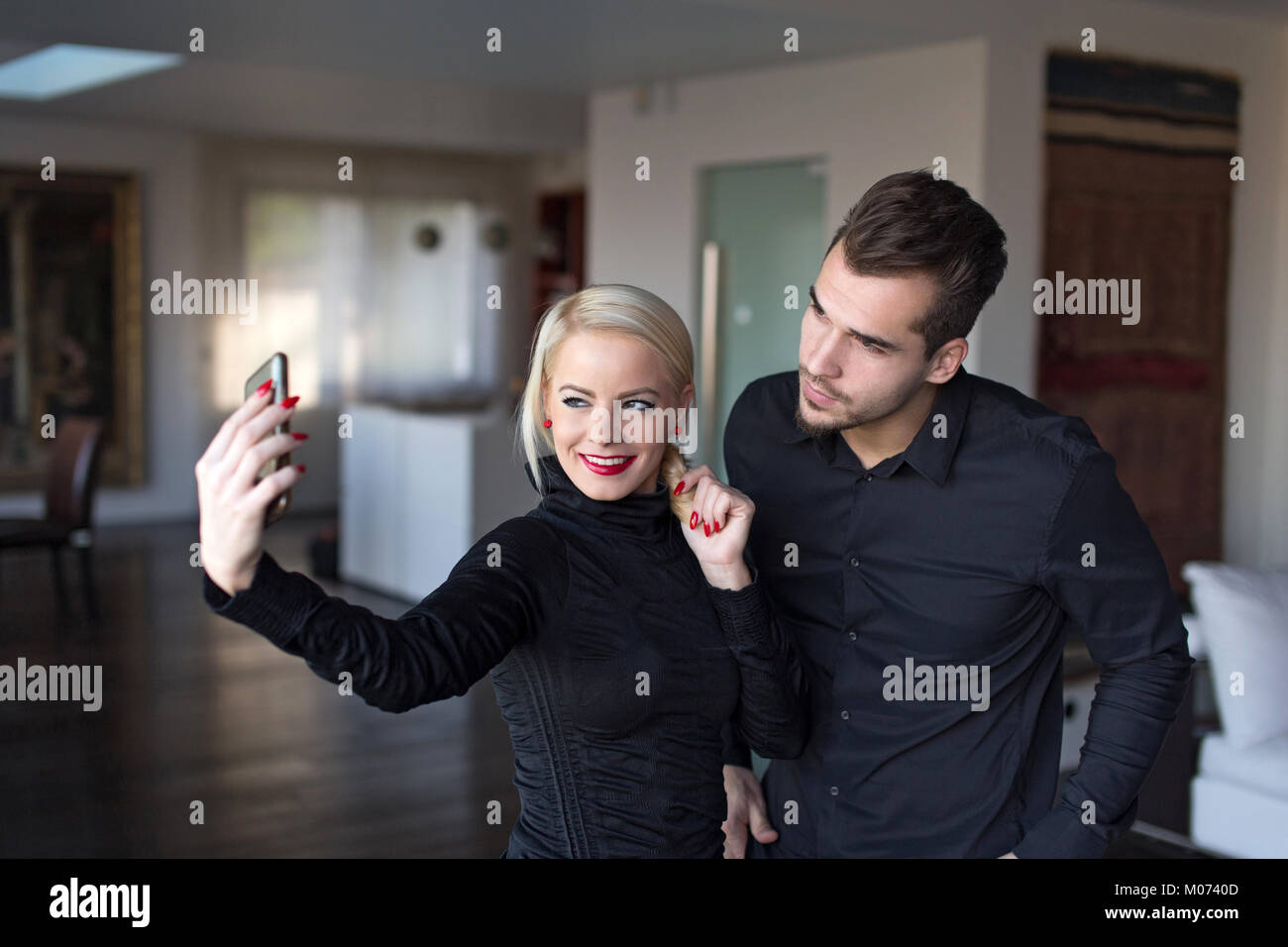 Glückliche junge elegante Paar in schwarzen Outfit unter selfie Indoor Stockfoto