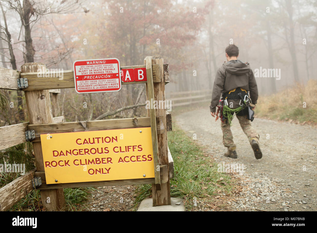 Eine Person mit Klettergeraeten an einem Warnschild am Pilot Mountain State Park, North Carolina, USA Stockfoto