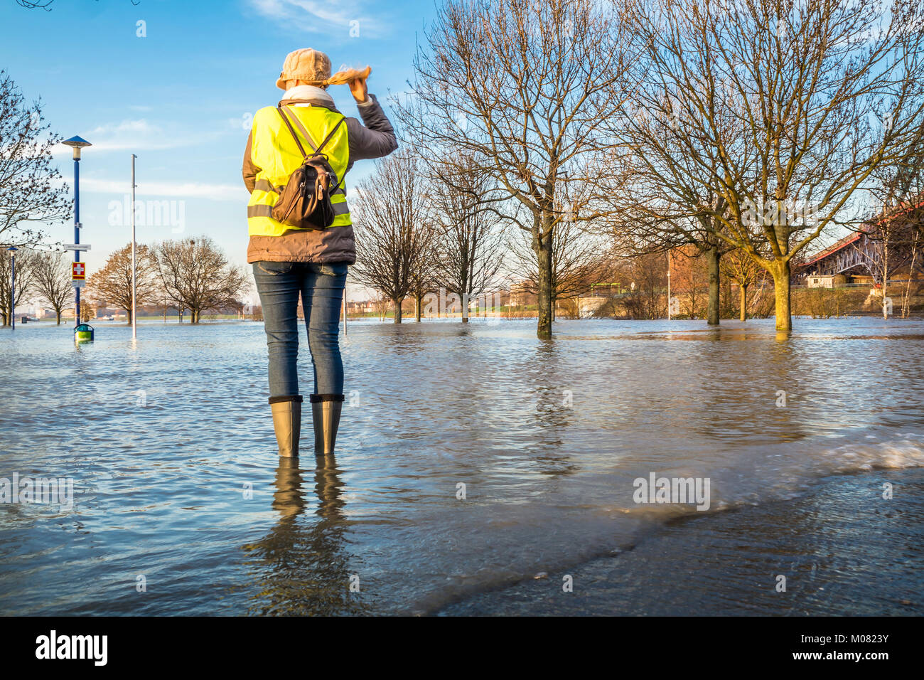 Frau in überfluteten Straße in wellys Stockfoto
