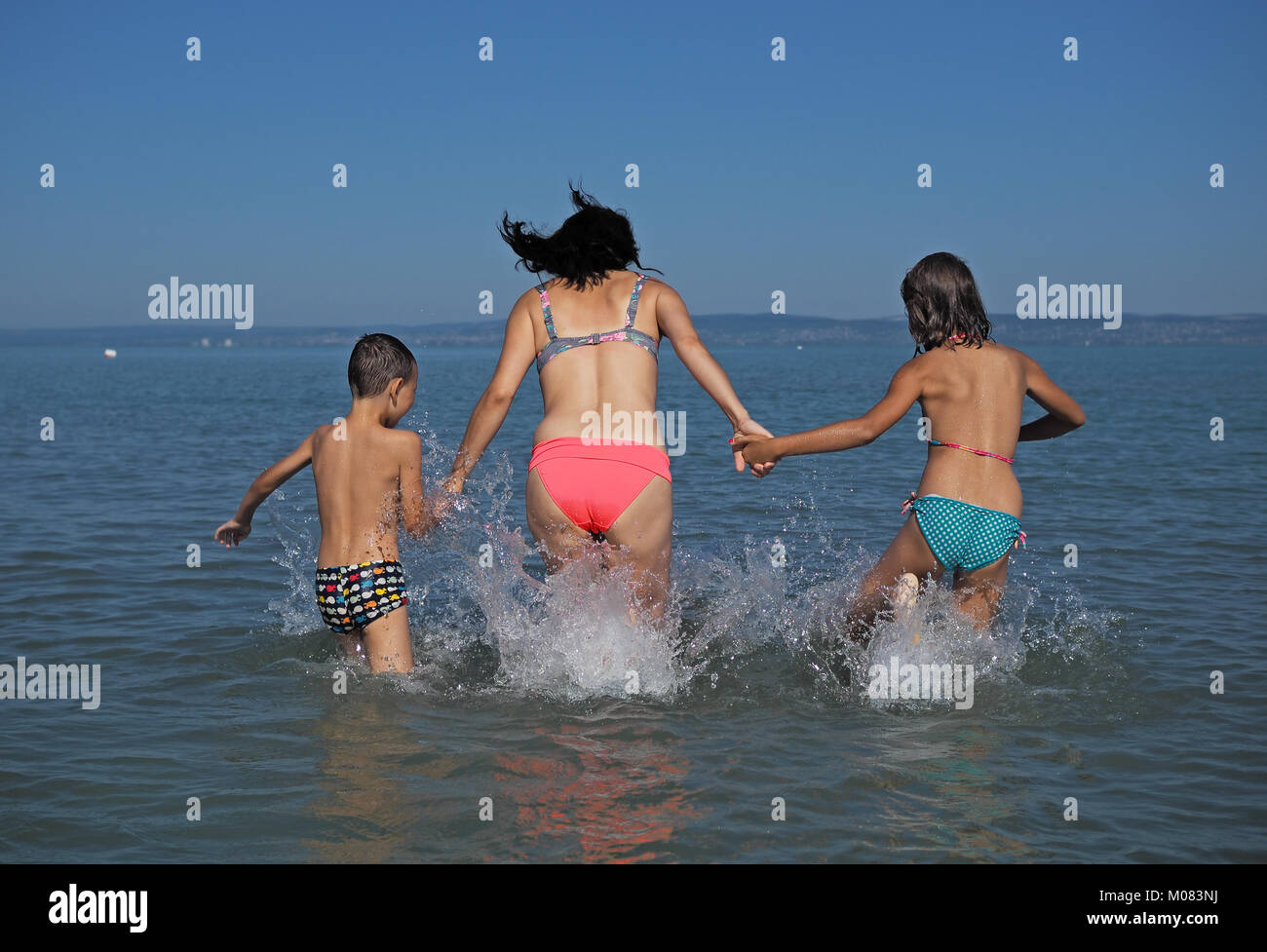 Mutter mit ihren Kindern beim Spielen im Wasser Stockfoto