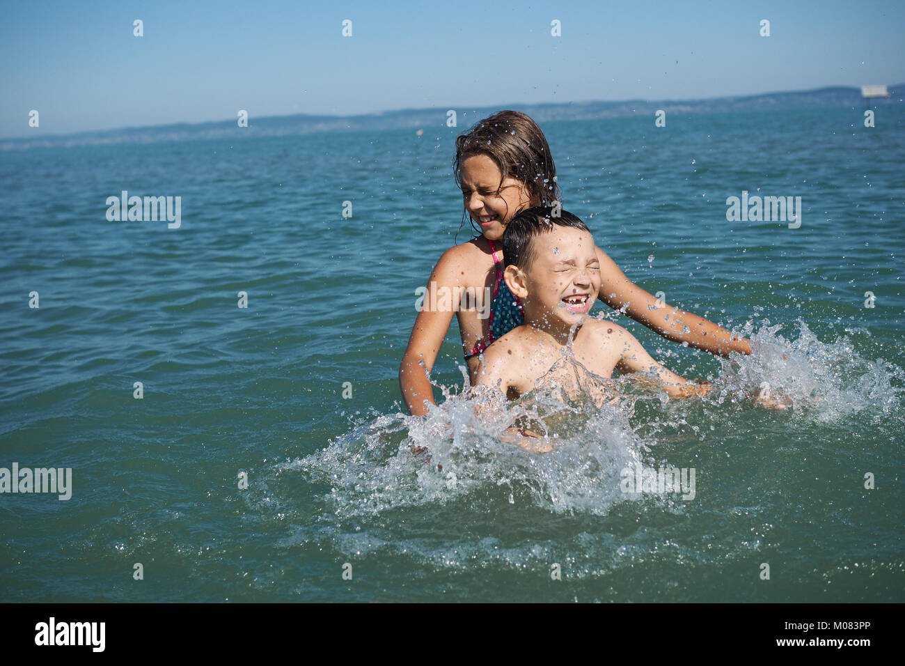 Kleines Mädchen und der kleine Junge spielt in Wasser Stockfoto