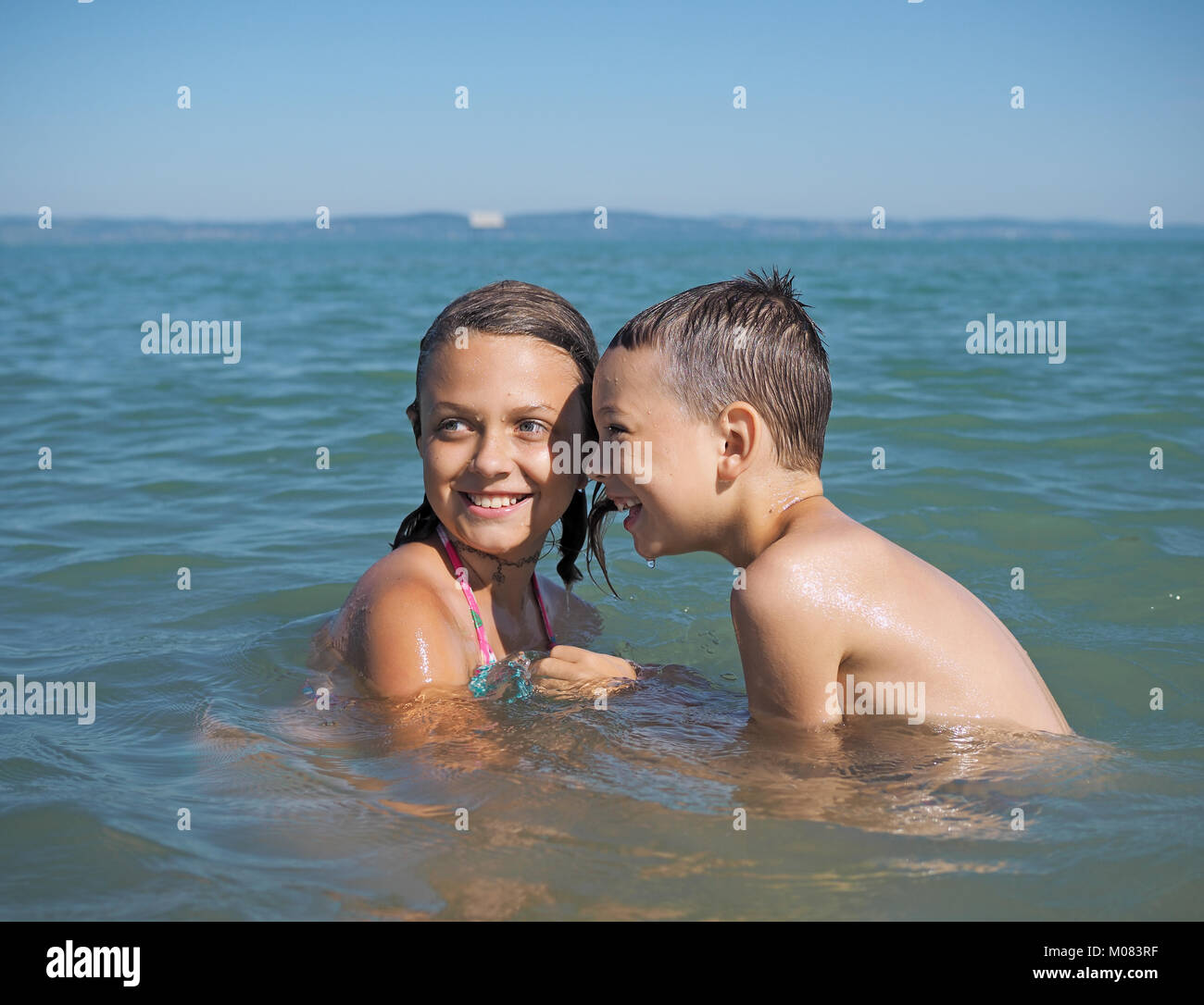 Kleines Mädchen und der kleine Junge spielt in Wasser Stockfoto