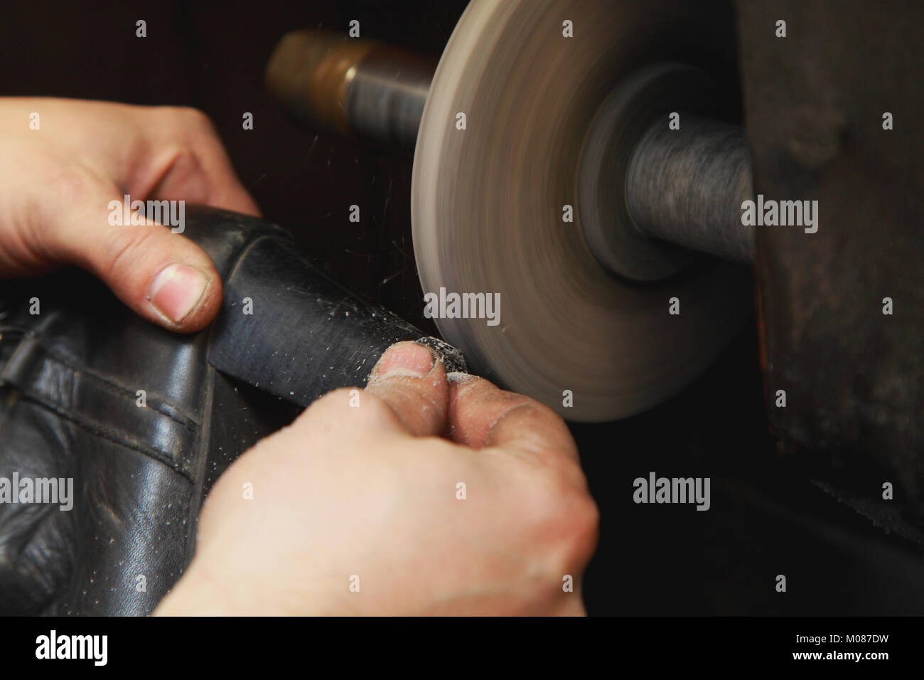 Ein Schuster arbeitet auf einer Schleifmaschine. Er schleift die Heels Damenschuhe Stockfoto