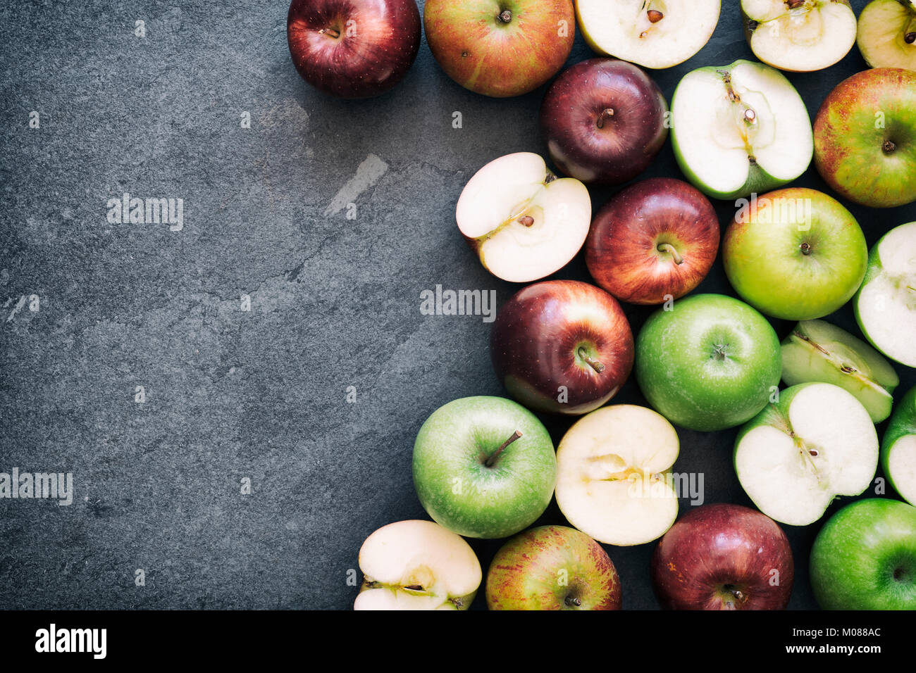 Rote und grüne Äpfel auf einer Schiefertafel Hintergrund Stockfoto