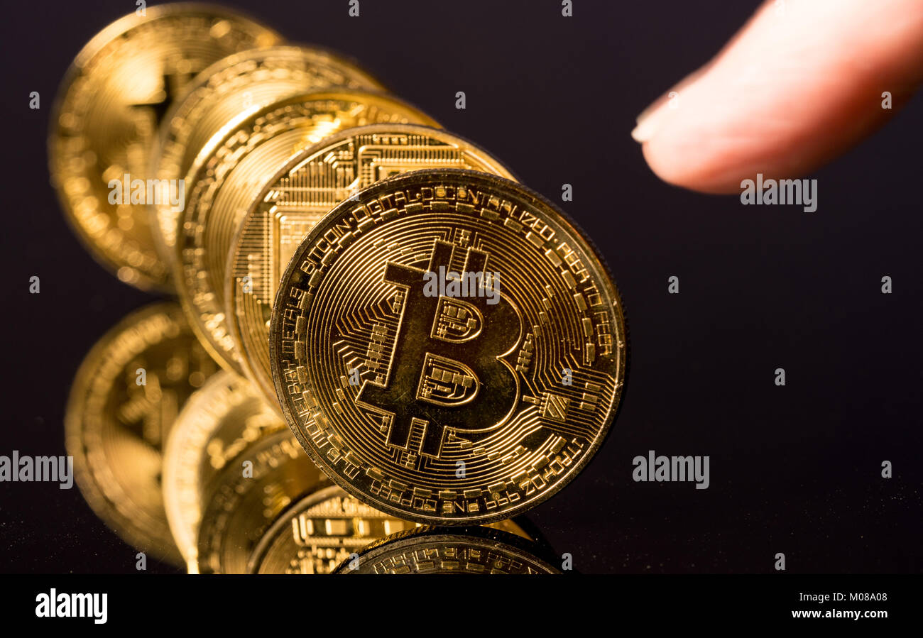 Bitcoins in einer Reihe stehen wie Dominosteine mit Finger Stockfoto
