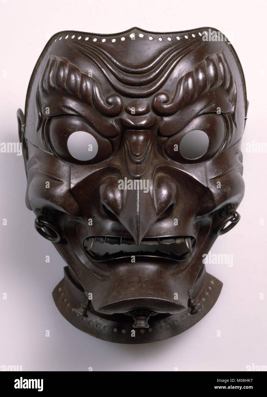Diese zeremonielle Maske zeigt detaillierte Gesichtszüge und hebt die künstlerische Handwerkskunst und kulturelle Praktiken ihrer Zeit hervor, die für rituelle oder theatralische Zwecke verwendet wurden. Stockfoto