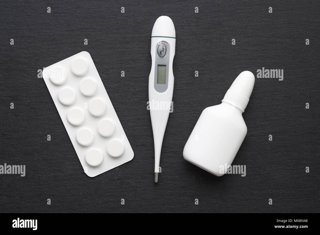 Thermometer, nasale Tropfen und Tabletten auf dunklem Schiefer. Flach. Medikamente für die Behandlung, Health Care Konzept Stockfoto