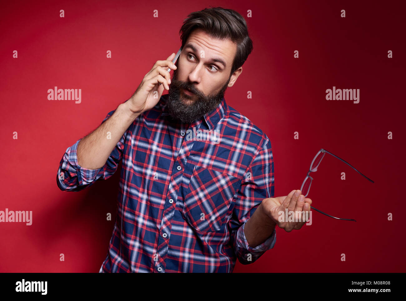 Mann per Handy im Studio shot Verwirrt Stockfoto