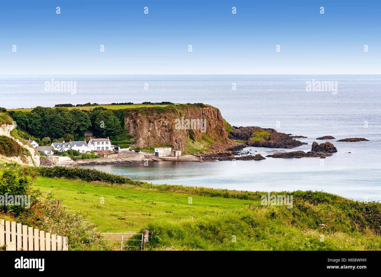 Atlantikküste mit einem steilen felsigen Klippen und Häuser im County Antrim, Nordirland, Großbritannien Stockfoto