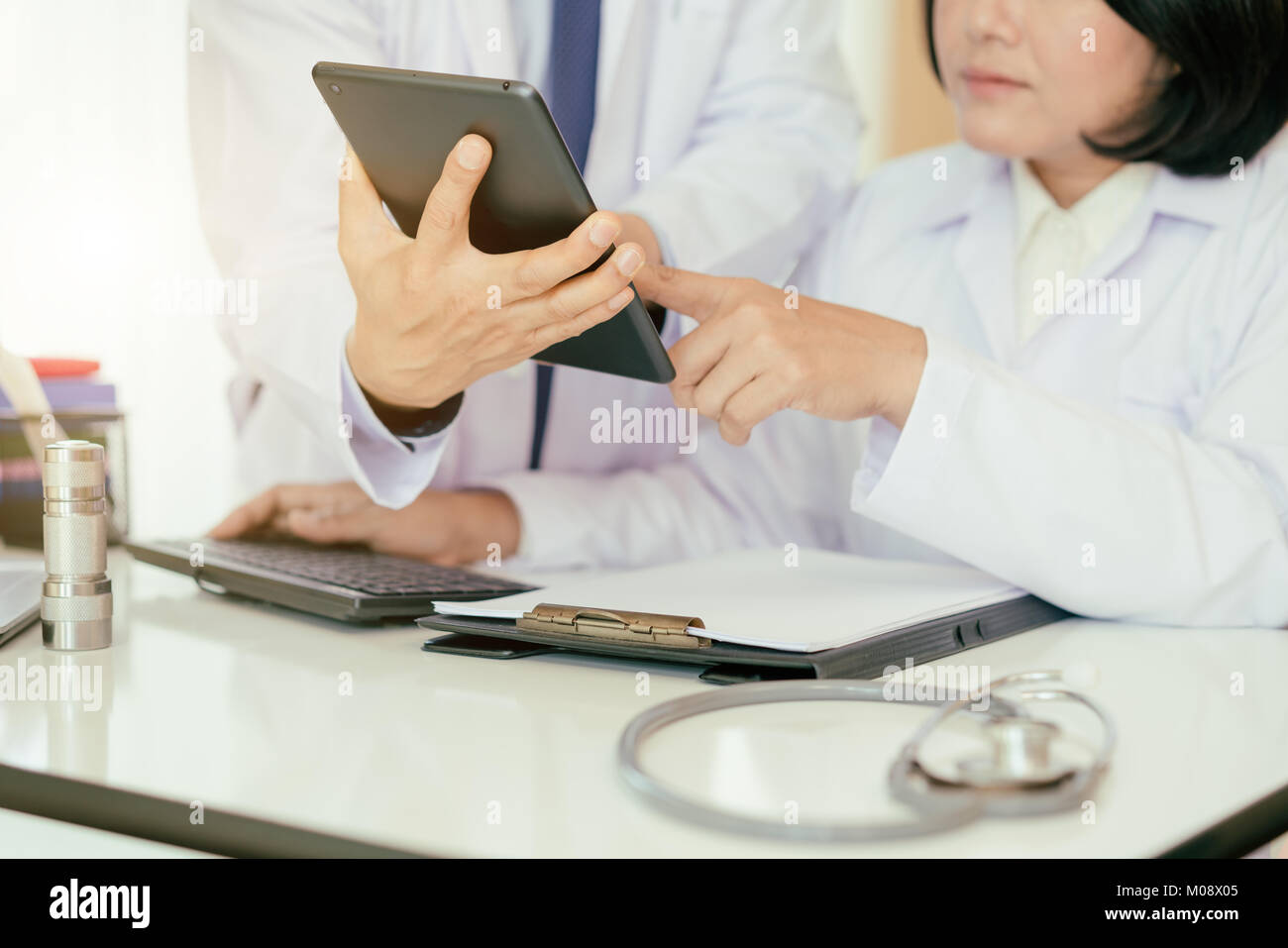 Zwei Doktoren der Analyse und Beratung über medizinische Aufzeichnung im modernen Krankenhaus. Asiatische Ärzte reden über Bericht. Stockfoto
