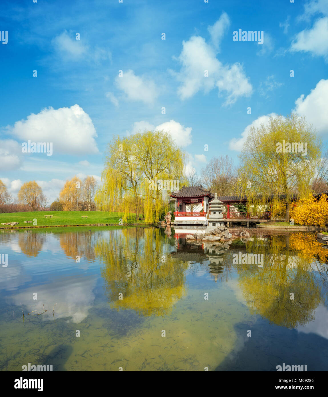 Stein Pagode im Teich von einem formellen Chinesischen Garten, Berlin, Deutschland. Konzentrieren Sie sich auf die steinernen Turm in der Mitte und die Gebäude Stockfoto