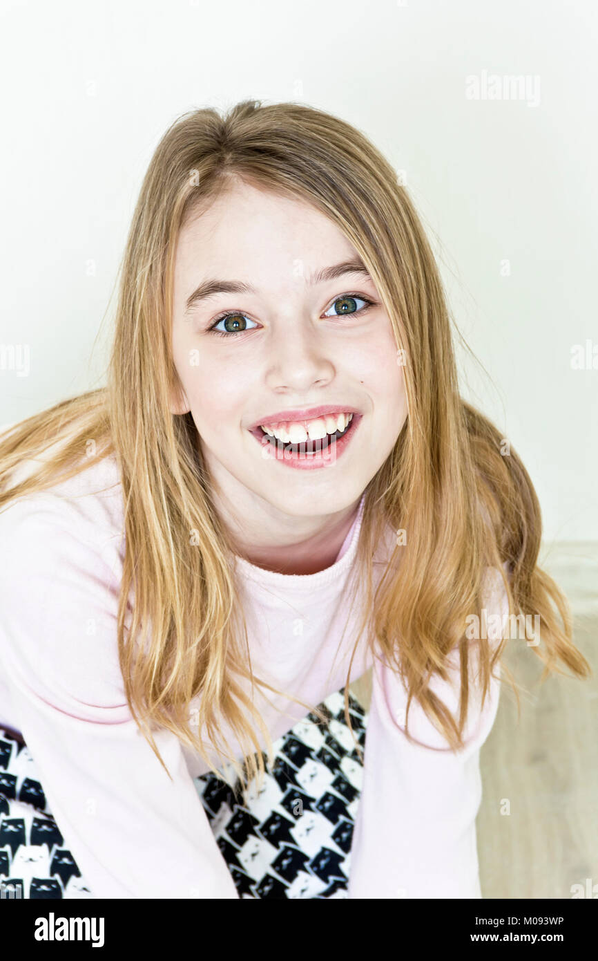 Lachende süße Mädchen 11 Jahre alt sind, sitzen auf dem Boden Stockfoto