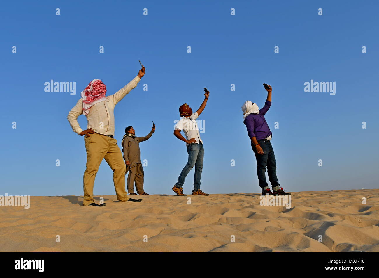 Gruppe von Männern die selfies in der Wüste und tragen ihre traditionellen Kopf Schals Stockfoto