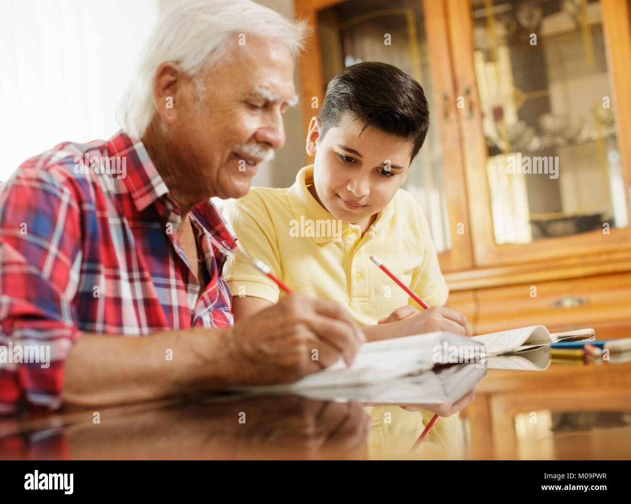 Kleiner Junge macht Schule Hausaufgaben mit alten Menschen zu Hause. Stockfoto