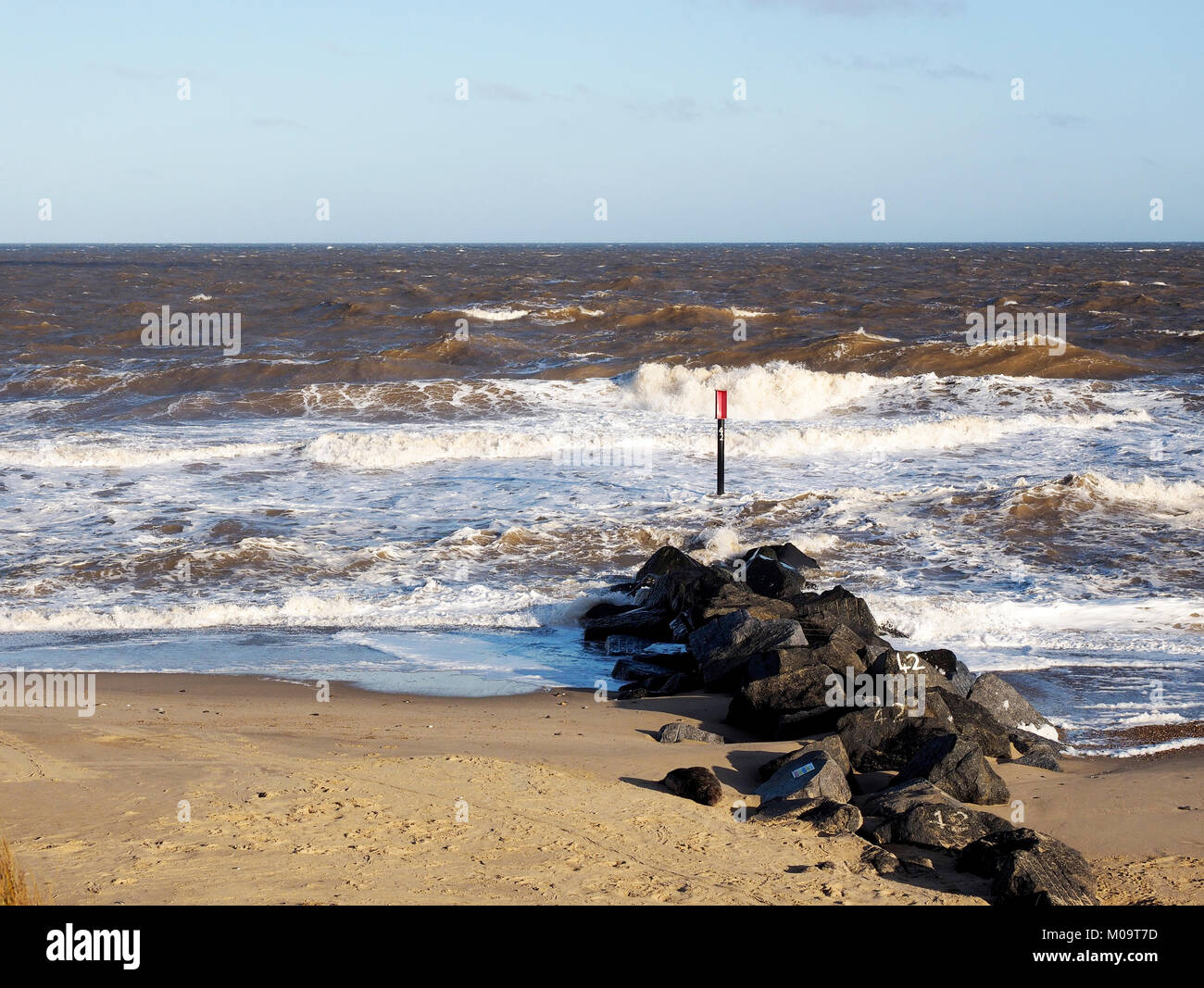 Stürmische Meere crash an Strand und Meer Barrieren an Horsey Lücke, Norfolk, Ort der berühmten Horsey Dichtungen Kolonie auf einem windgepeitschten Januar Tag. Stockfoto