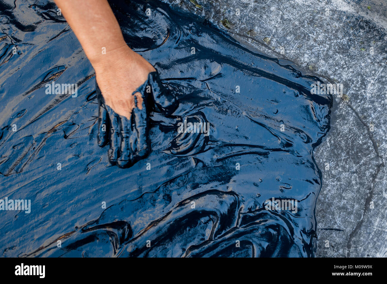 Eine salvadorianische Landarbeiter breitet sich die Indigo Paste auf einem Blech Tisch bei der Herstellung in der Nähe von San Miguel, El Salvador. Stockfoto