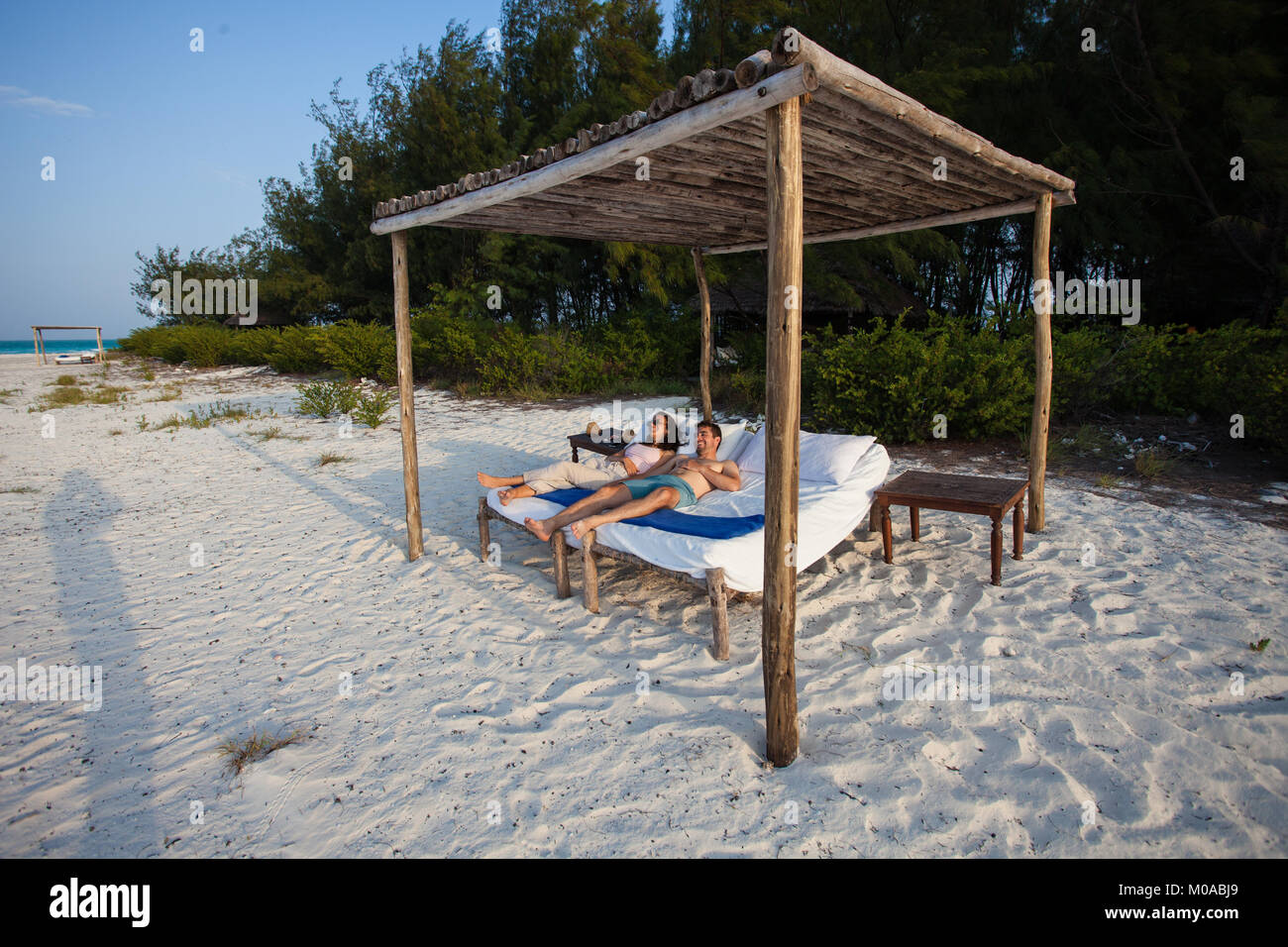 Ein junges Paar entspannt am Strand Kissen im Schatten ihrer Cabana Stockfoto